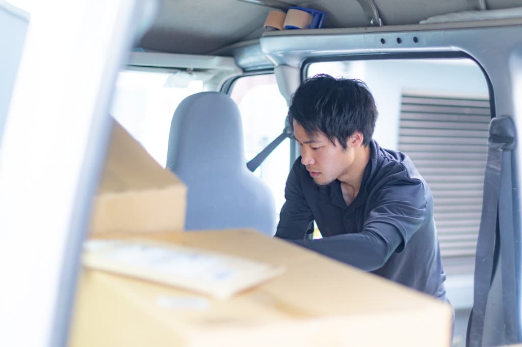 軽貨物車内で荷物を仕分けするドライバー