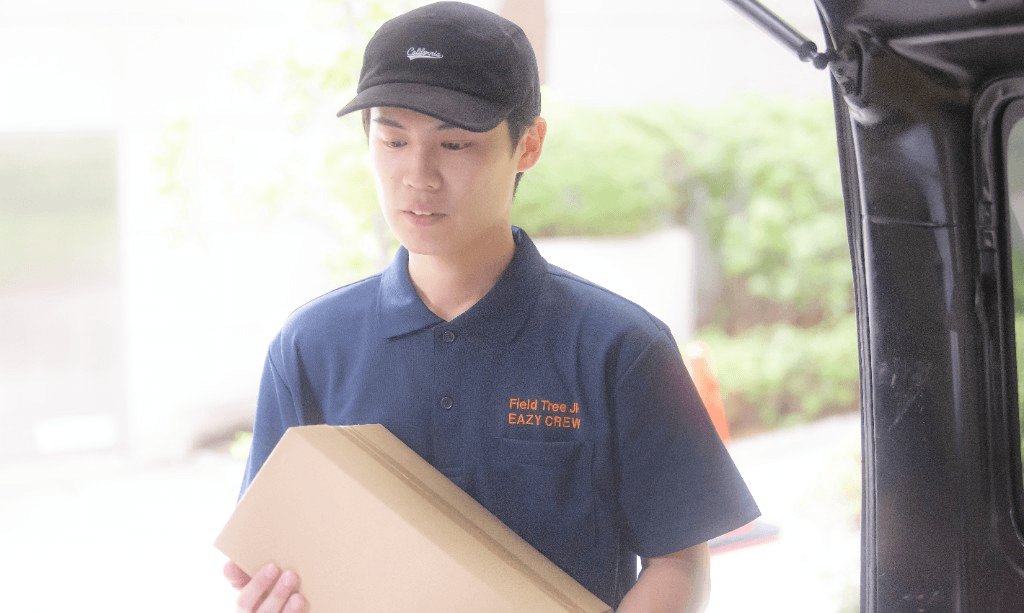 荷物を両手で持ち配送するドライバー