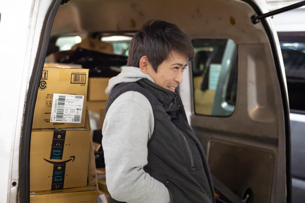 配送車両の前で荷物を確認するスタッフ